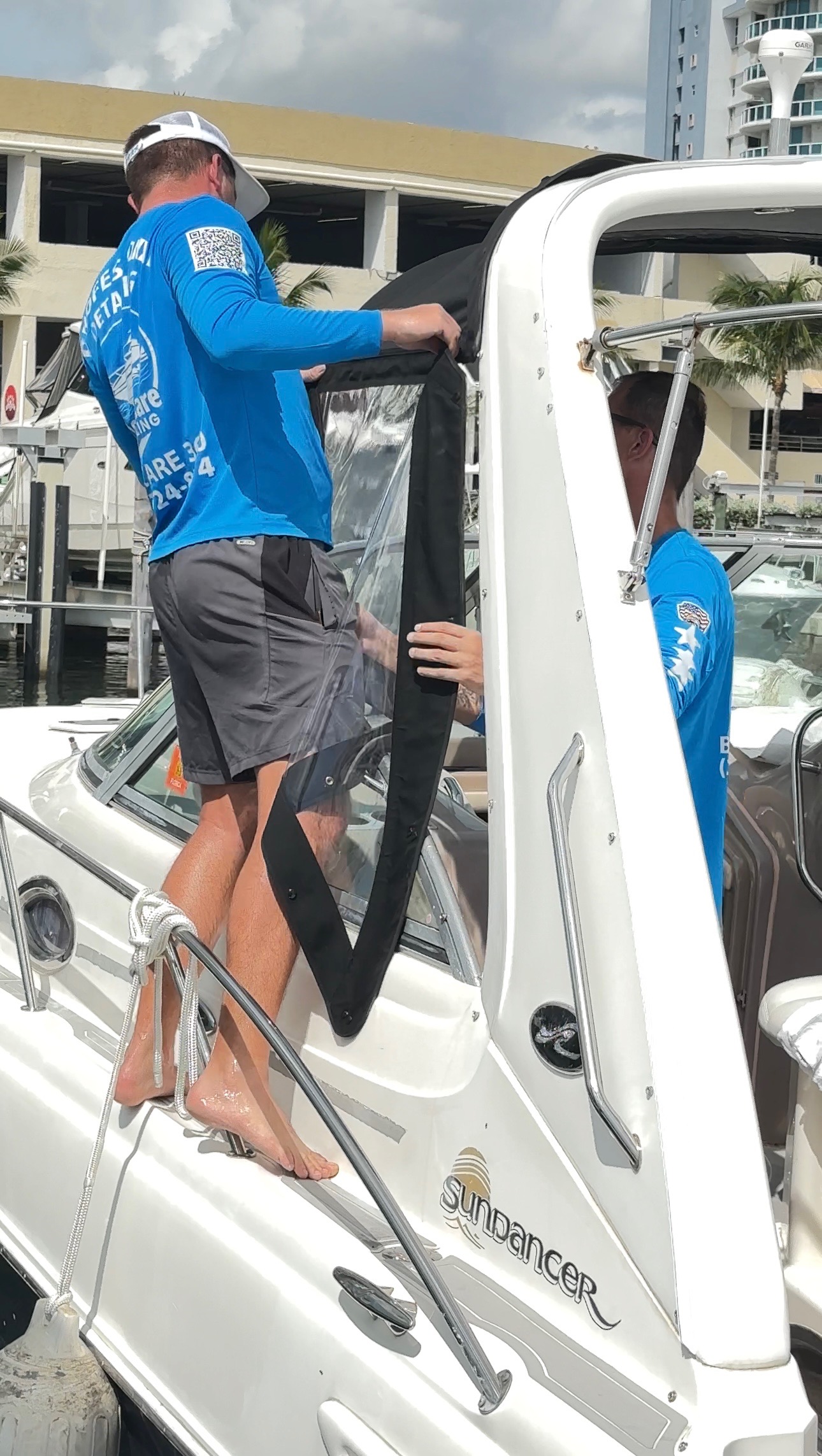 BoatCare360 team cleaning Sundancer boat canvas at marina with palm trees